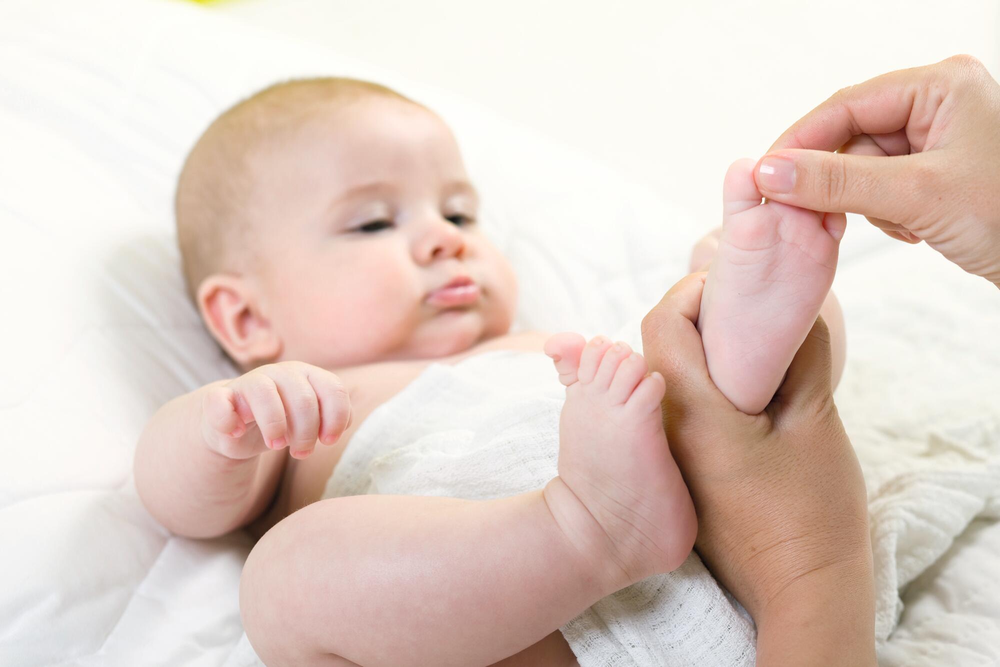 Baby som ligger ned mens en voksen holder foten.